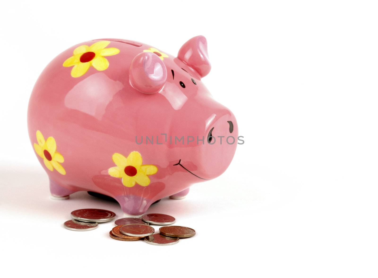 Pink ceramic piggy bank with loose coins around.