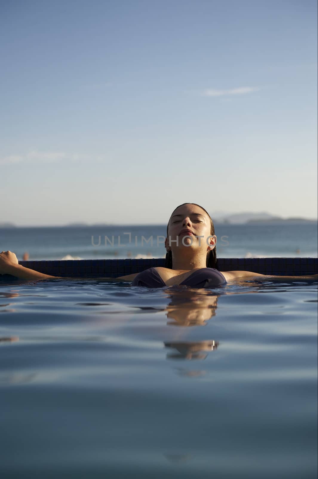 Woman relaxing on a swimming pool with a sea view in Rio de Janeiro, Brazil