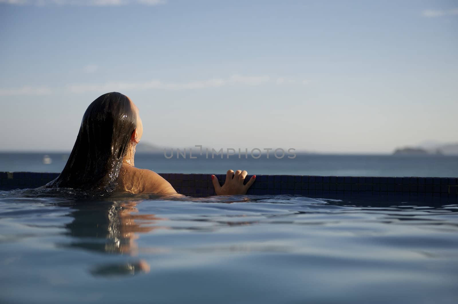 Woman relaxing on a swimming pool with a sea view in Rio de Janeiro, Brazil