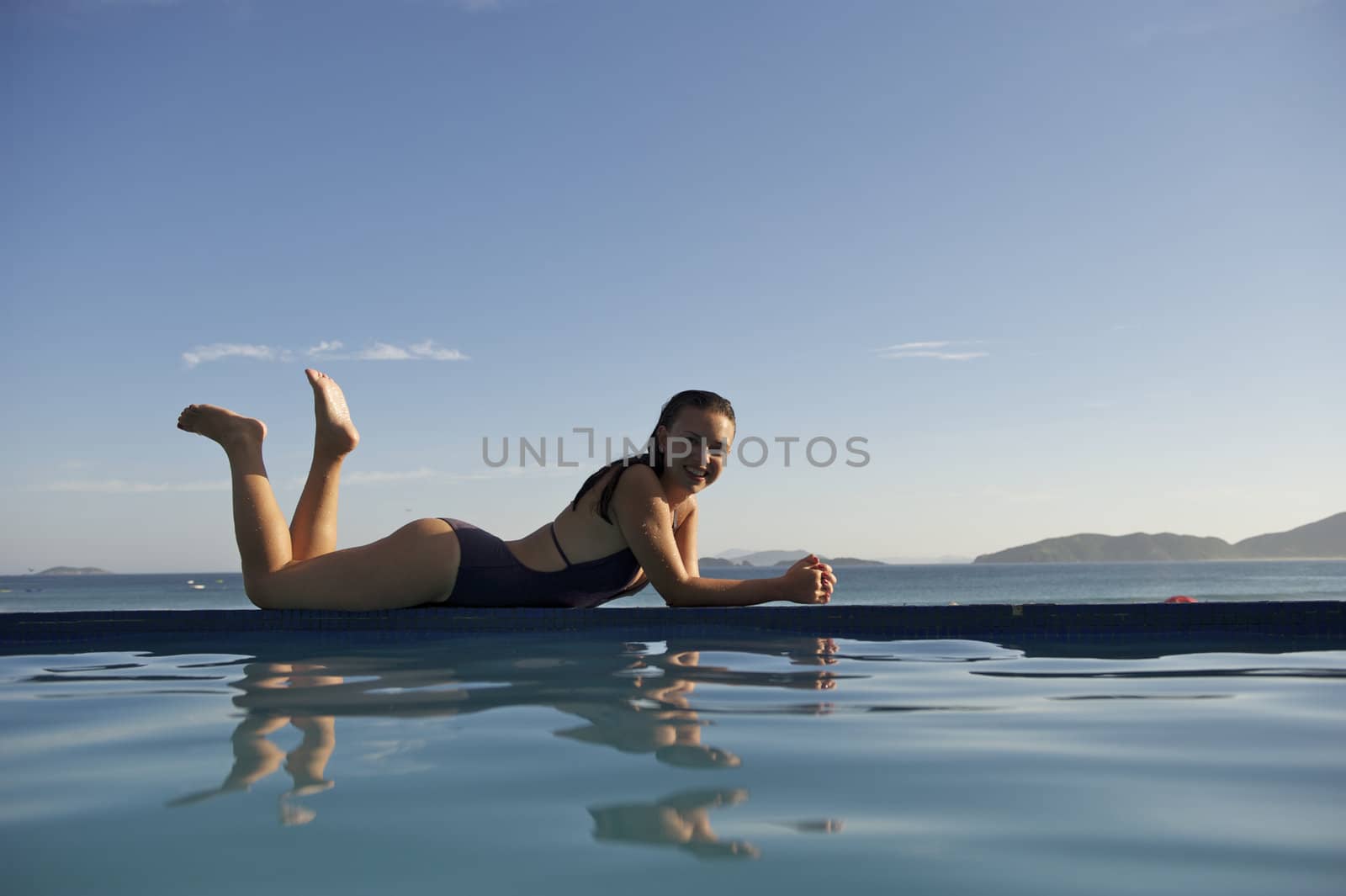 Woman relaxing on a swimming pool with a sea view in Rio de Janeiro, Brazil
