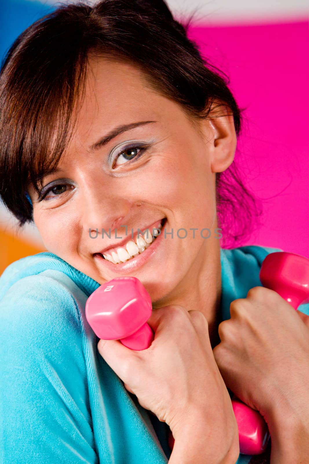 Beautiful young woman curls dumbbells with a happy smile