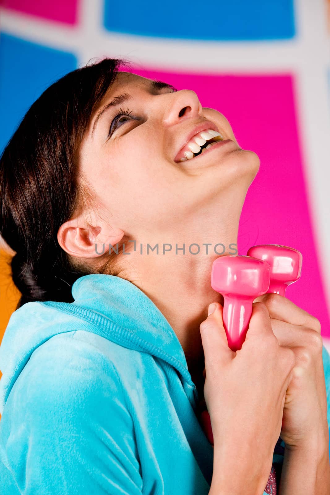 Beautiful young woman curls dumbbells with a happy smile