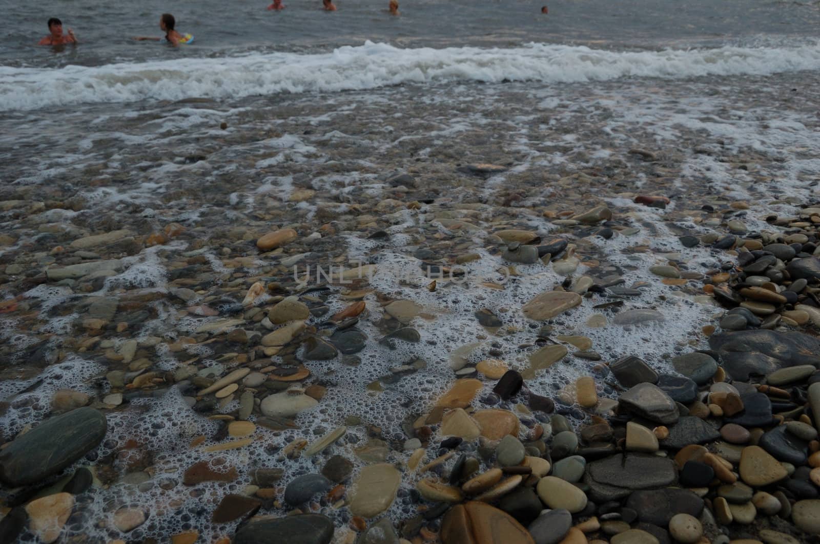 closeup of sea shore with pebbles covered with film of water