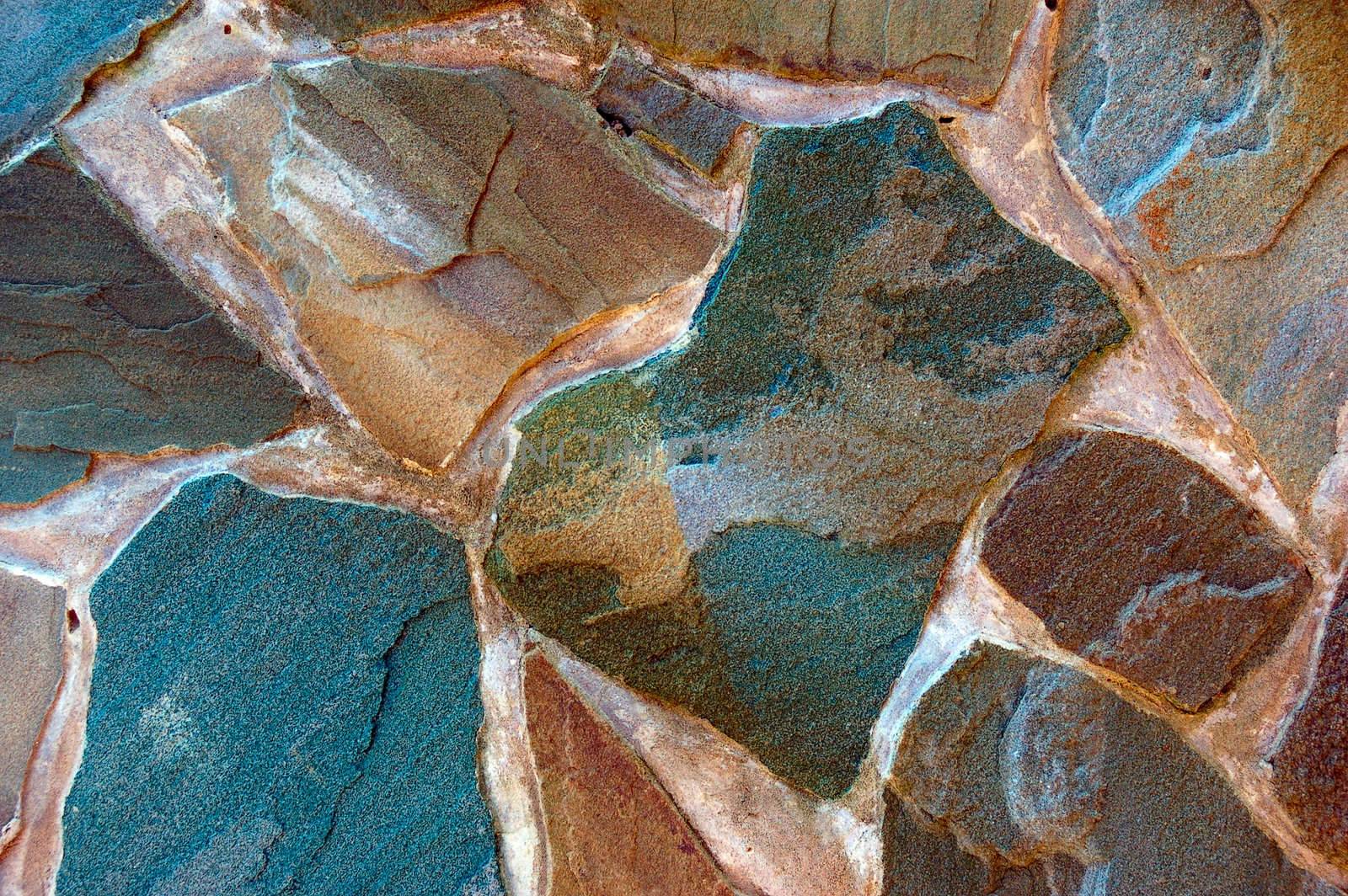 colored (prevaling blue and brown) rough wall surface made of wild stones