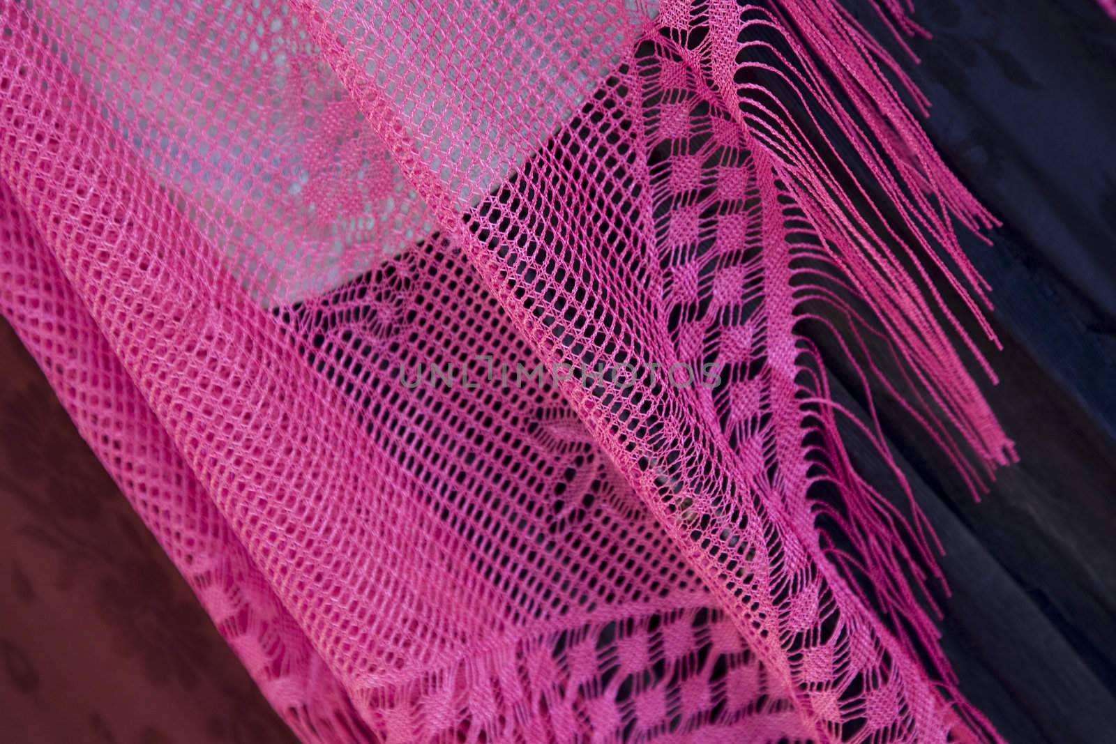 A pink lace shawl on a dark background.