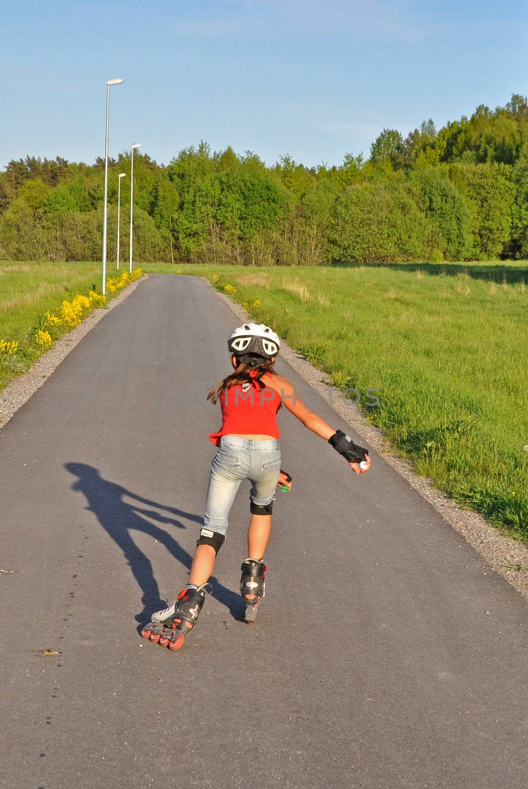 A young girl is skating away on her inlines on a warm summer evening.