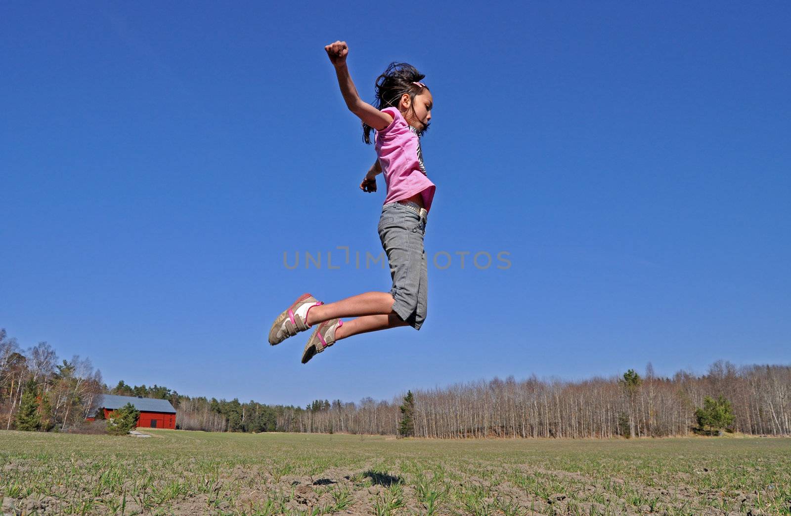 A young girl jumps in the countryside, happy that the spring finally has arrived.