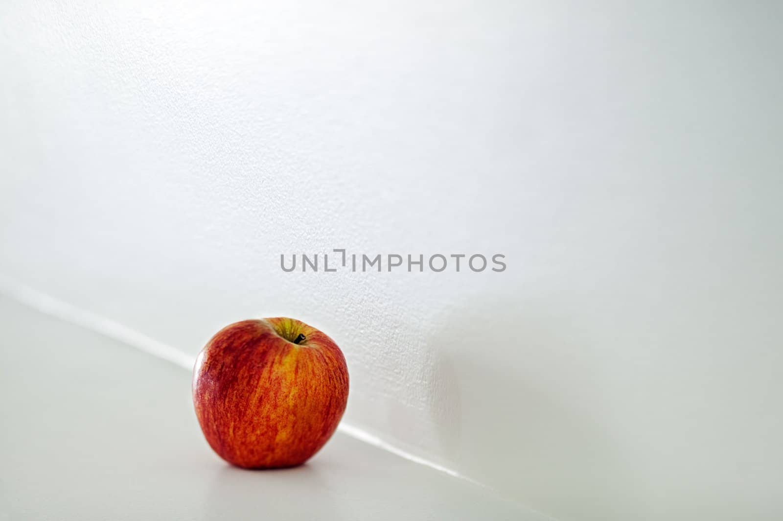 A red apple on a fireplace mantle.