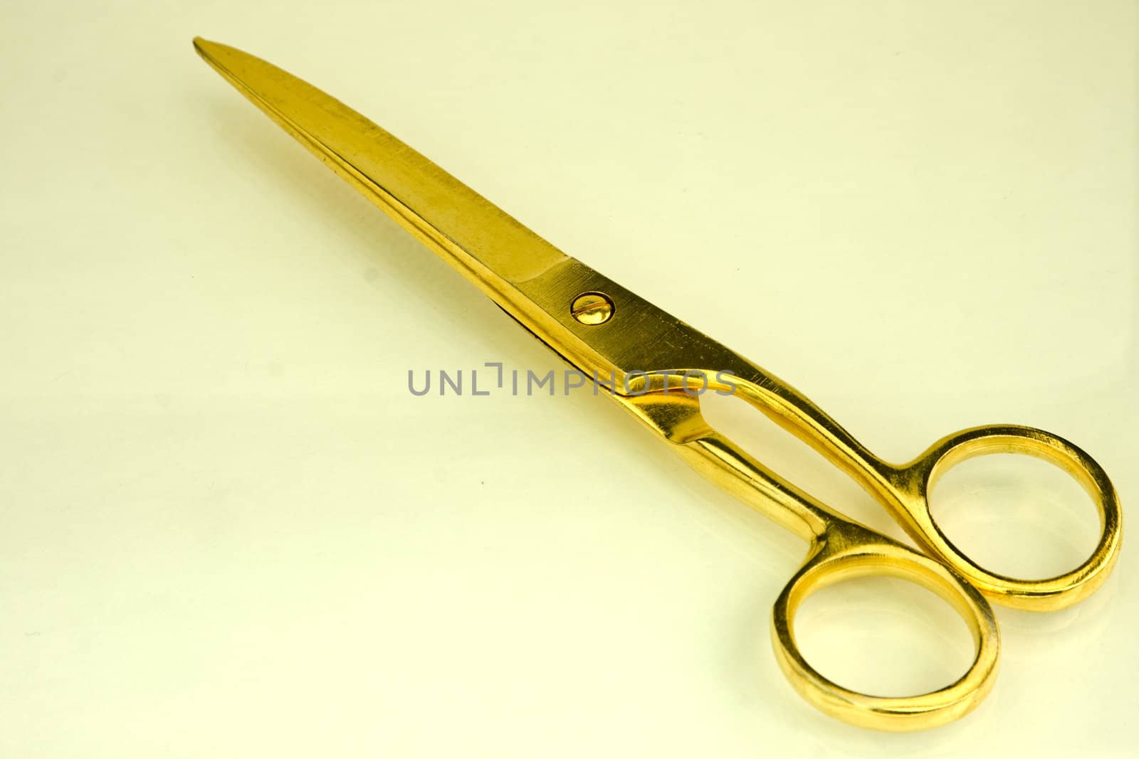 Modern goldl scissors on a yellow background