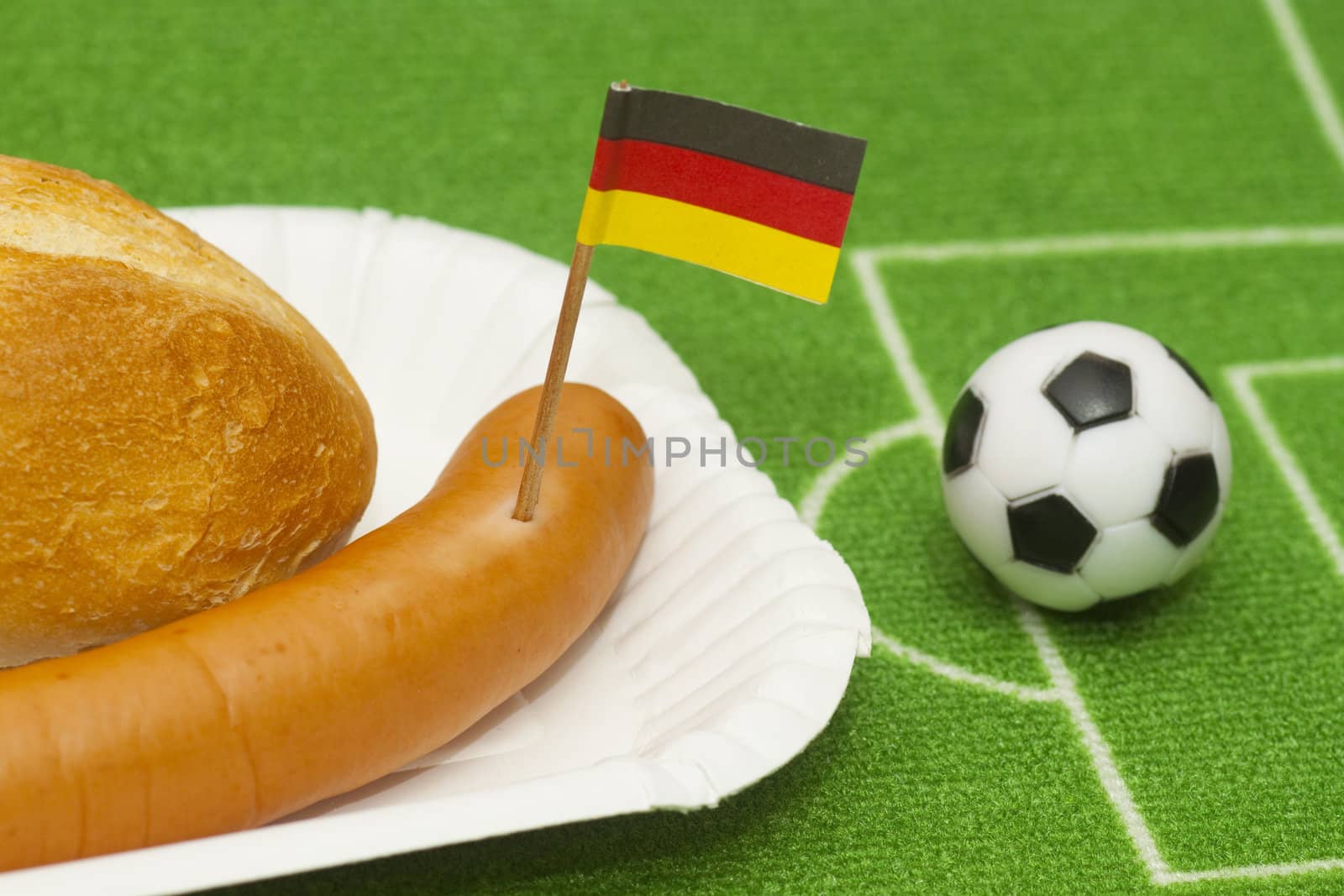 Sausage with roll on a football field background with soccer ball