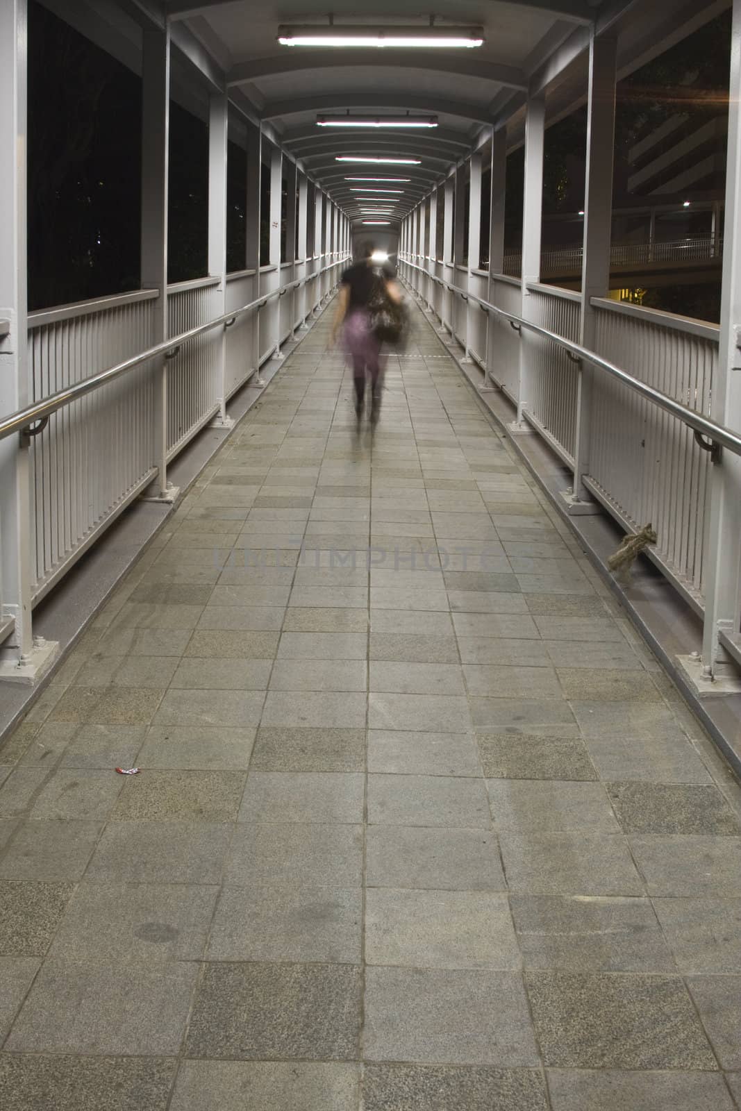 a woman walking on flyover to go home at night.