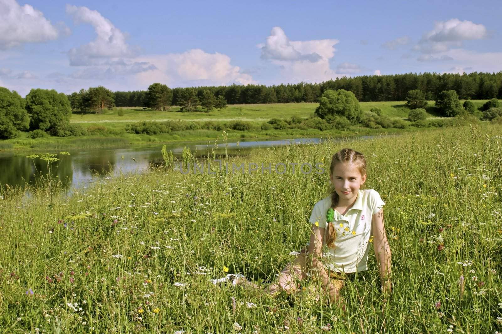 Young girl on meadows around the river. Russia, summer
