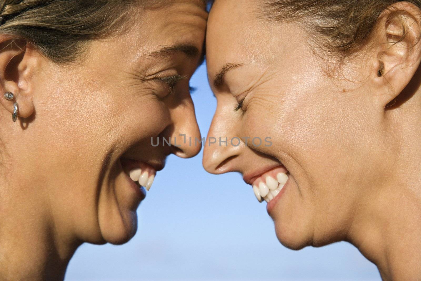 Women head to head smiling. by iofoto
