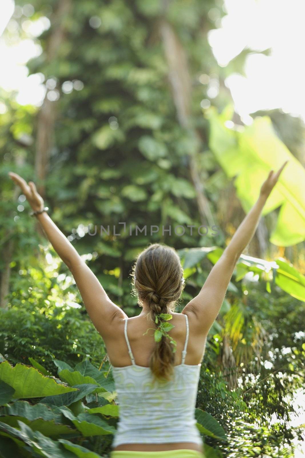 Rear view of Caucasian mid-adult woman holding arms out in yoga position.