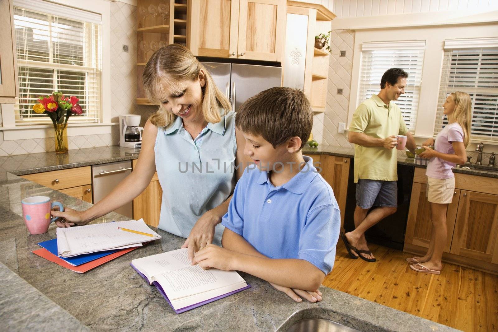 Caucasian family in kitchen doing homework and chatting.