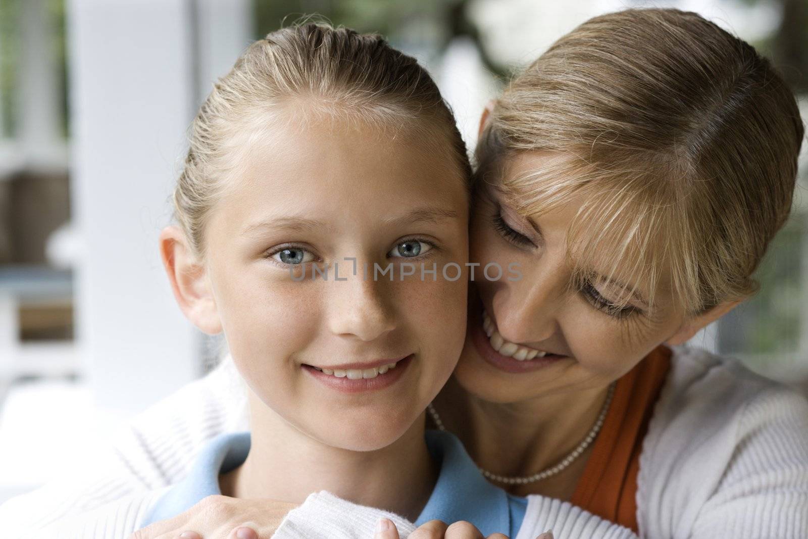 Caucasian mid-adult mother hugging pre-teen daughter.