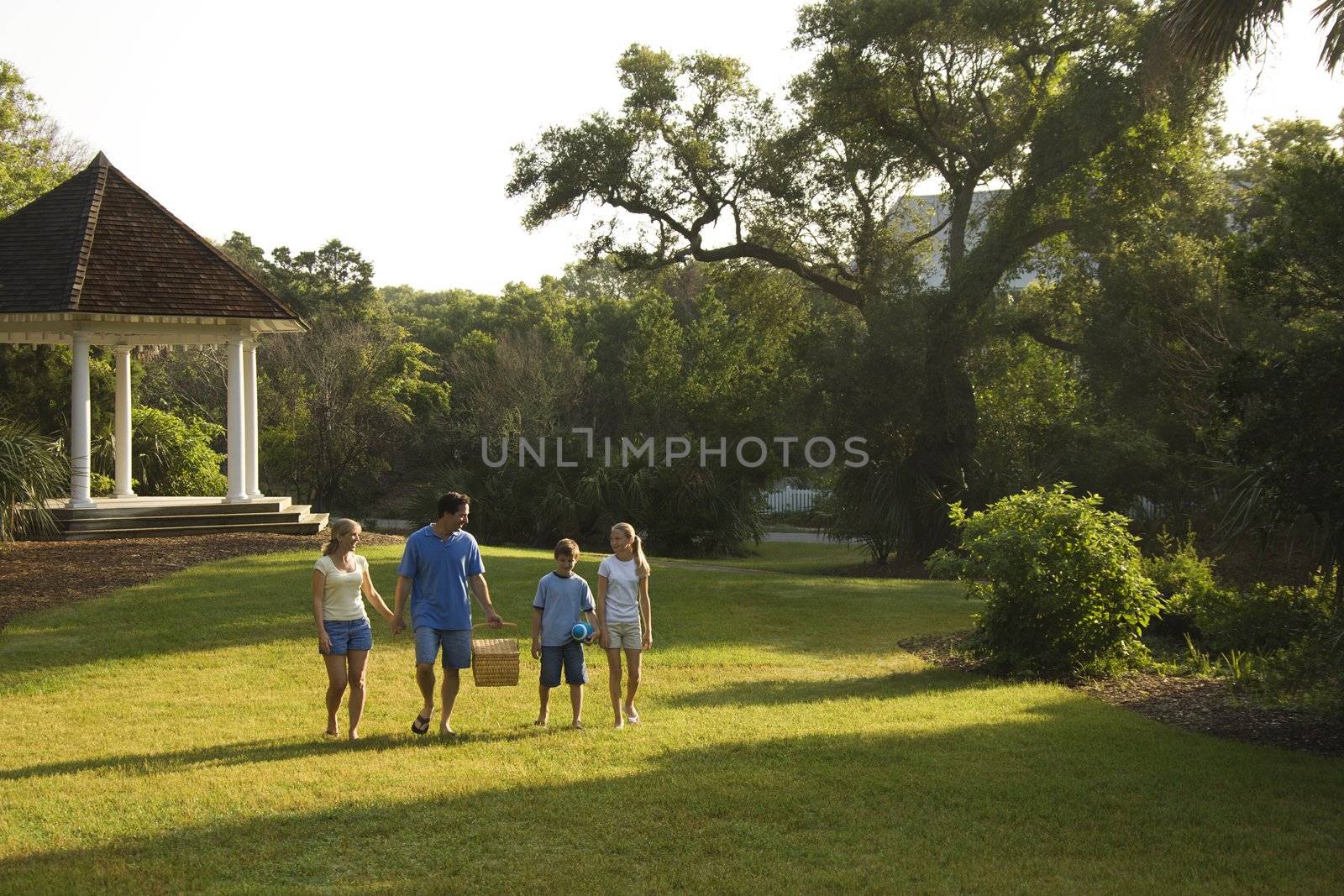 Family walking in park. by iofoto