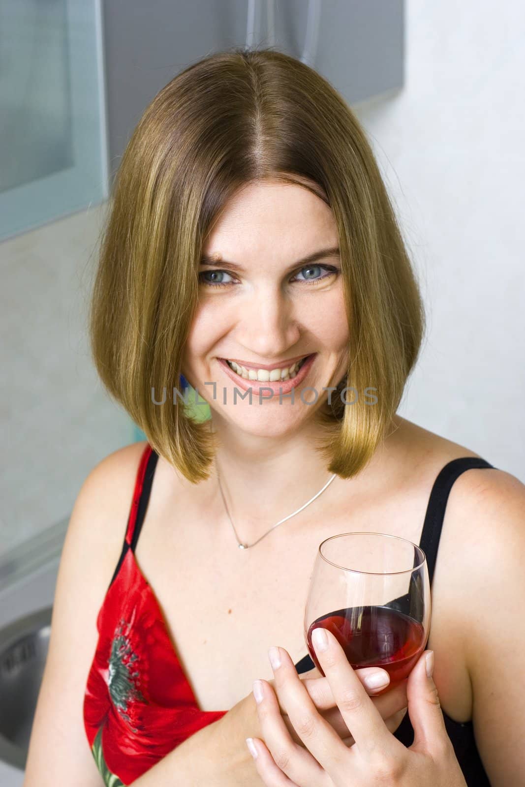 Young woman on kitchen witn red wine