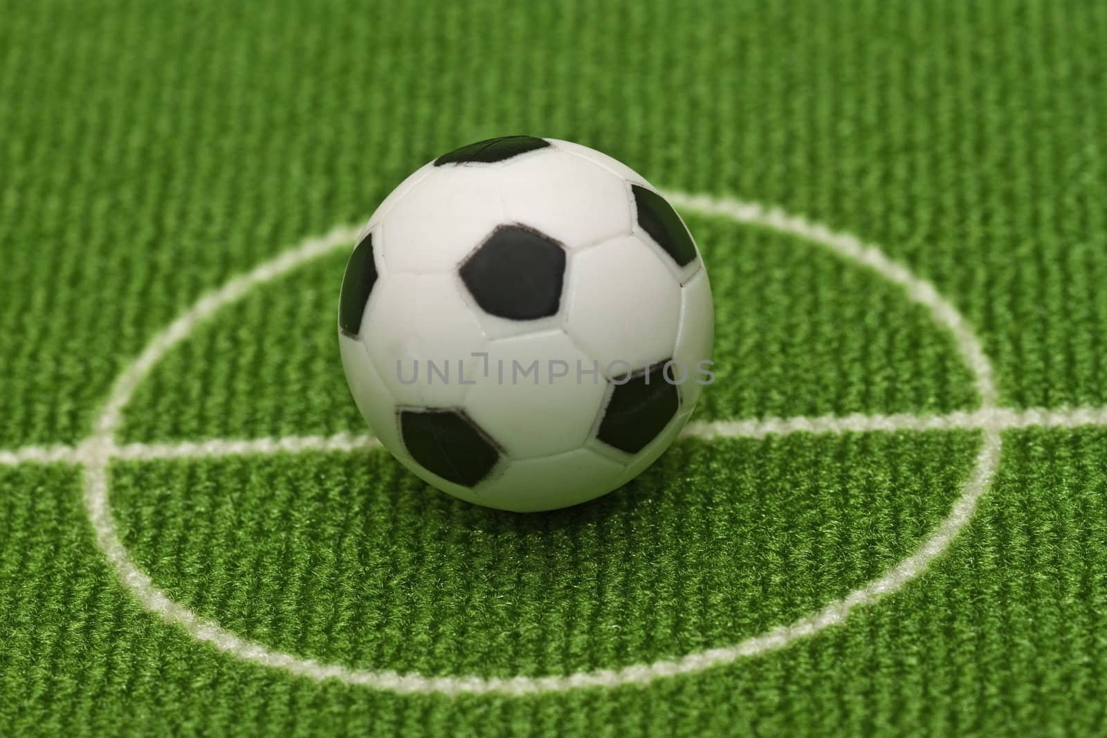 Symbol photo toy soccer ball on a football field. Shot in studio.