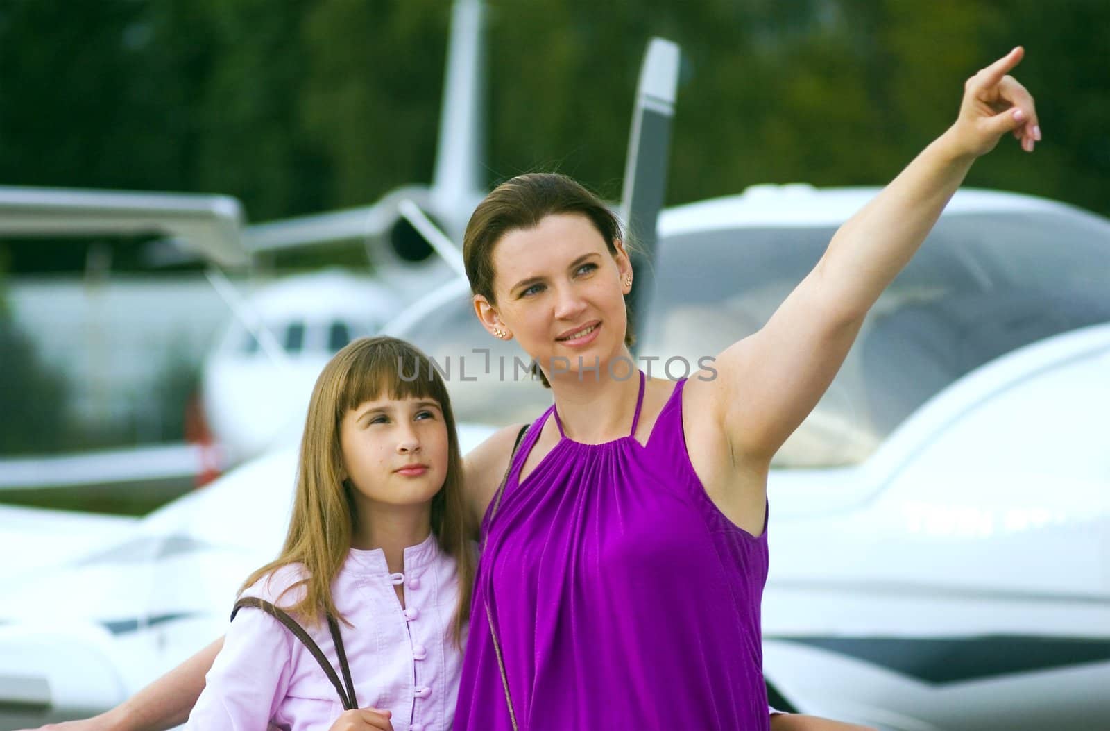 Mother looking daughter to airplane on front view.