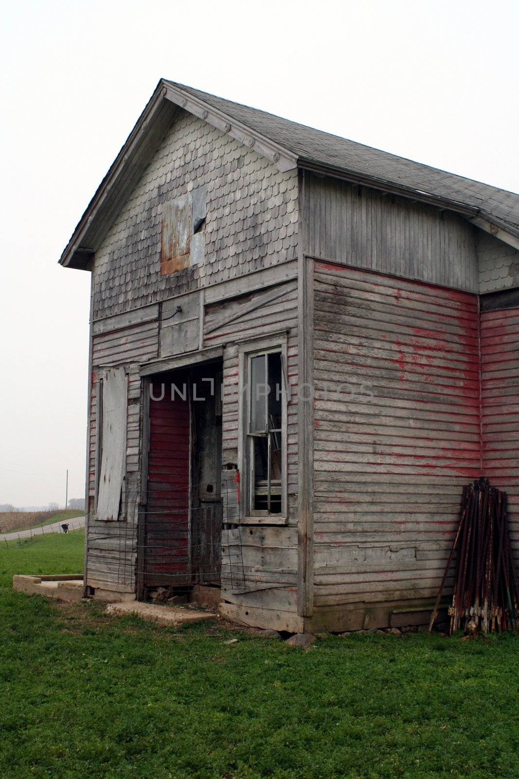 An old one room school house in a field on a cloudy day.