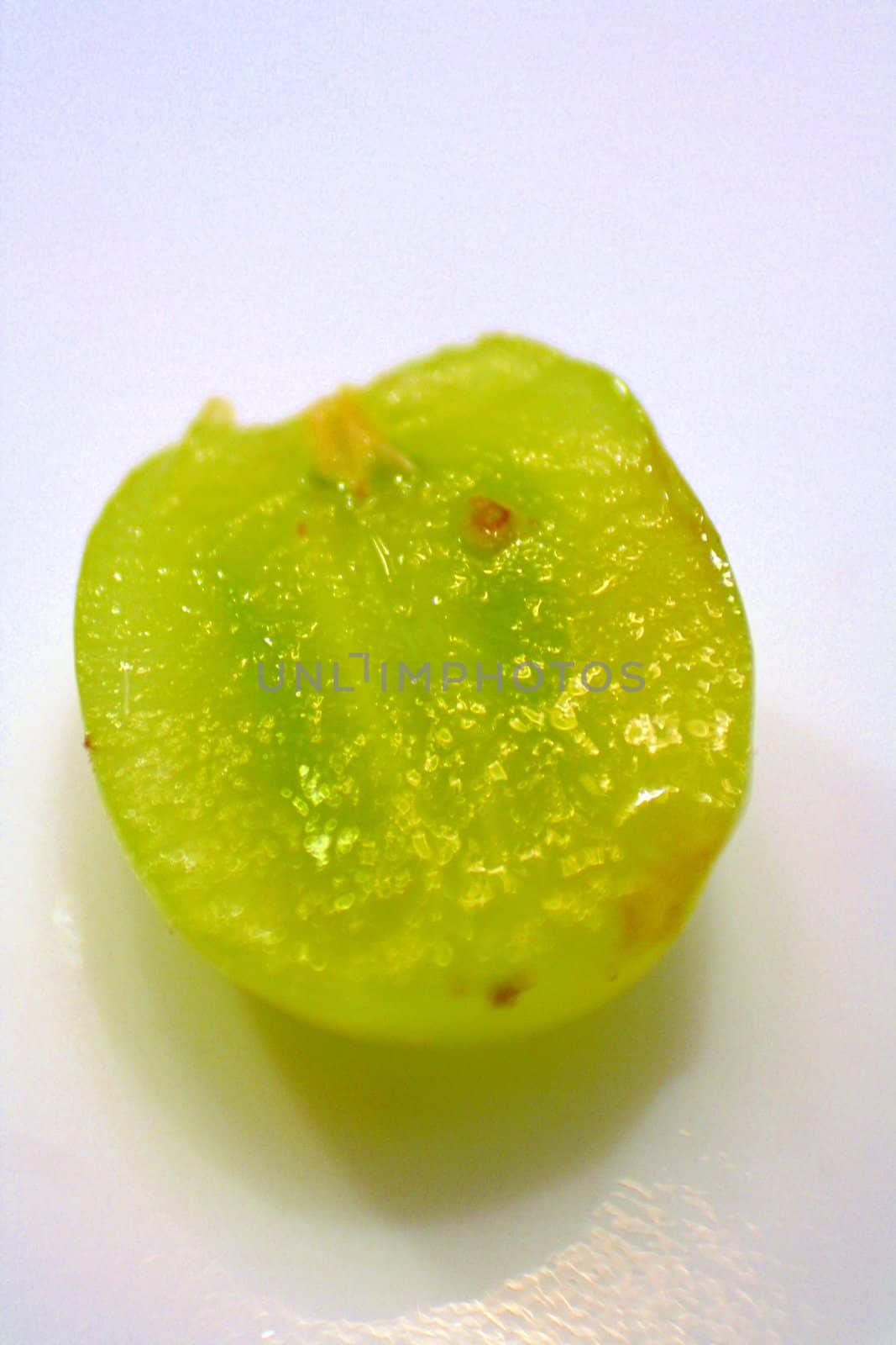 A very close up detail of a sliced grape on a white background.