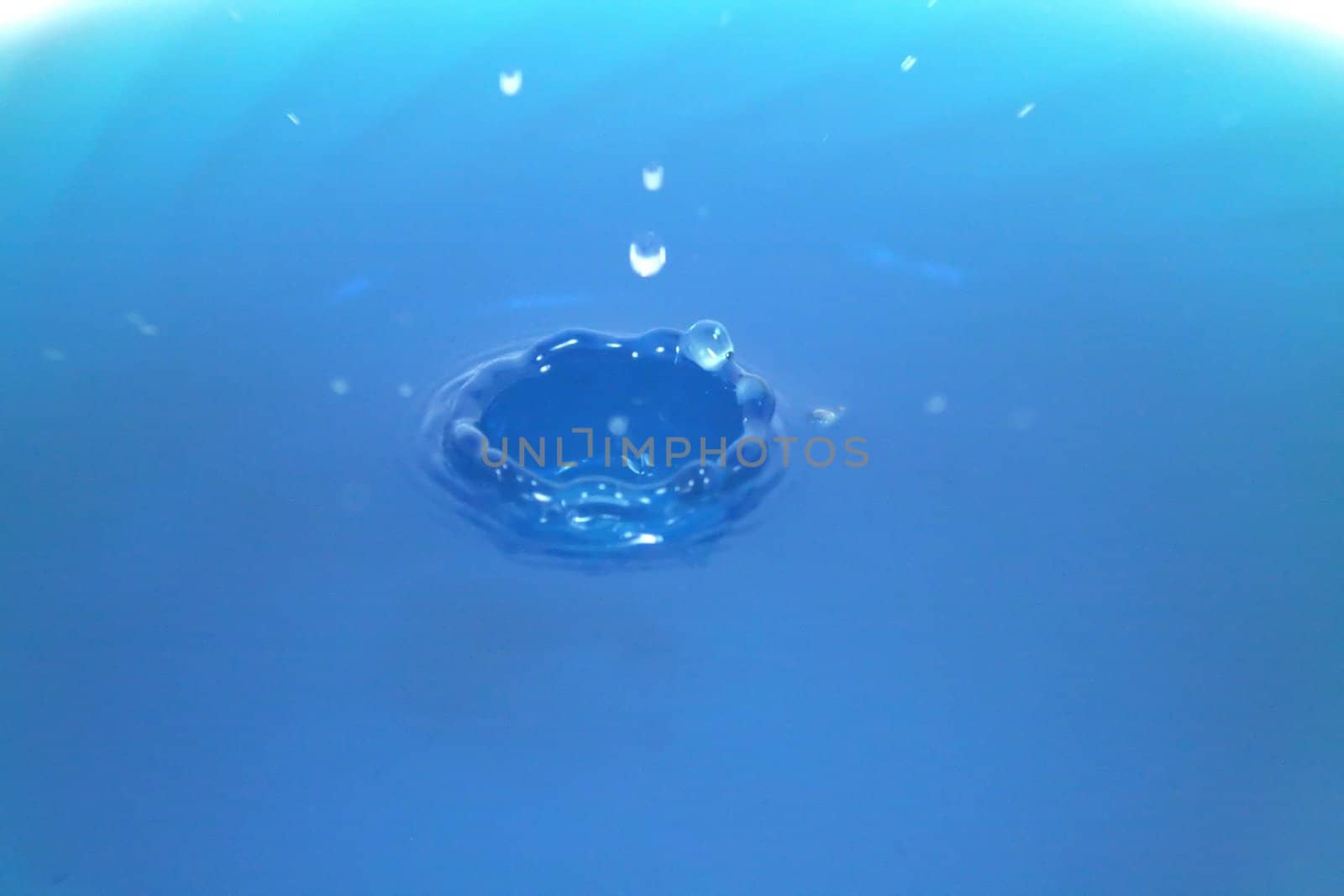 A crown of water rising out of a blue liquid.
