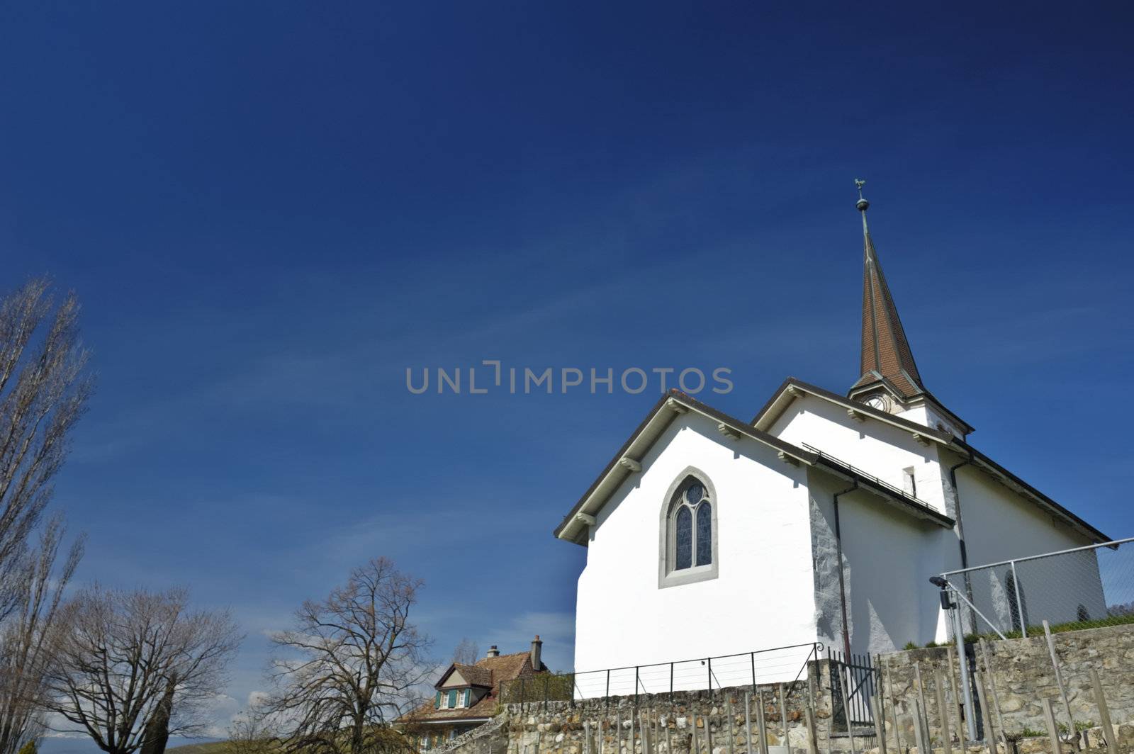 The church in the Swiss wine-growing village of Fechy. Space for copy in the clear blue sky.