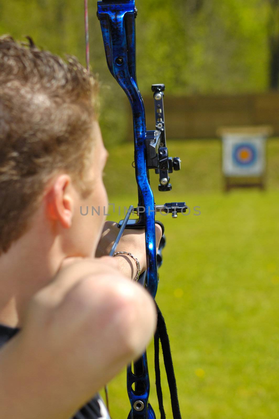 An archer aims at the bullseye of a distant target. Selective focus on the arrow in the bow.