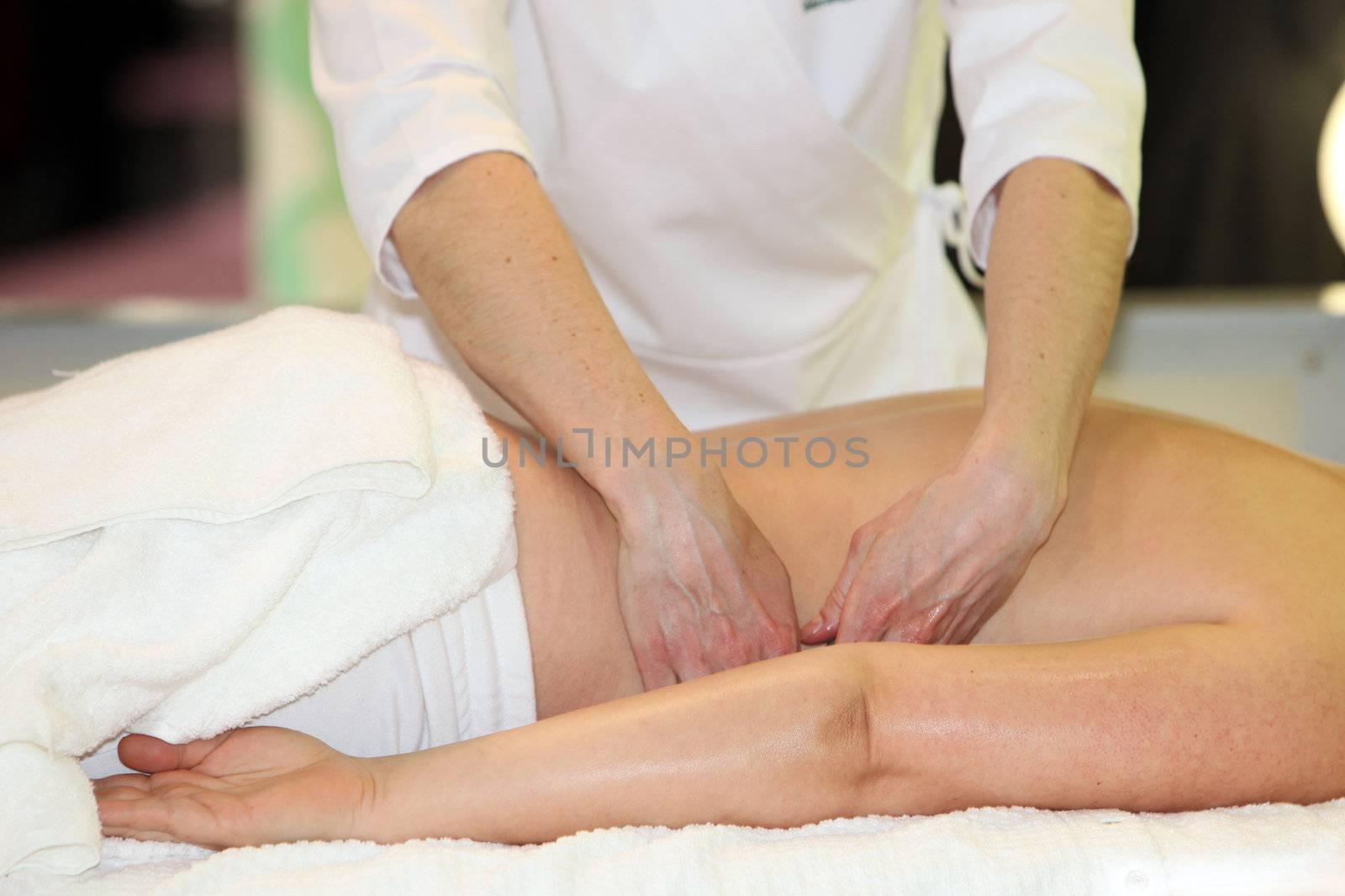A woman receives a massage - you lies relaxed on a massage table. The hands of the masseuse masi back.