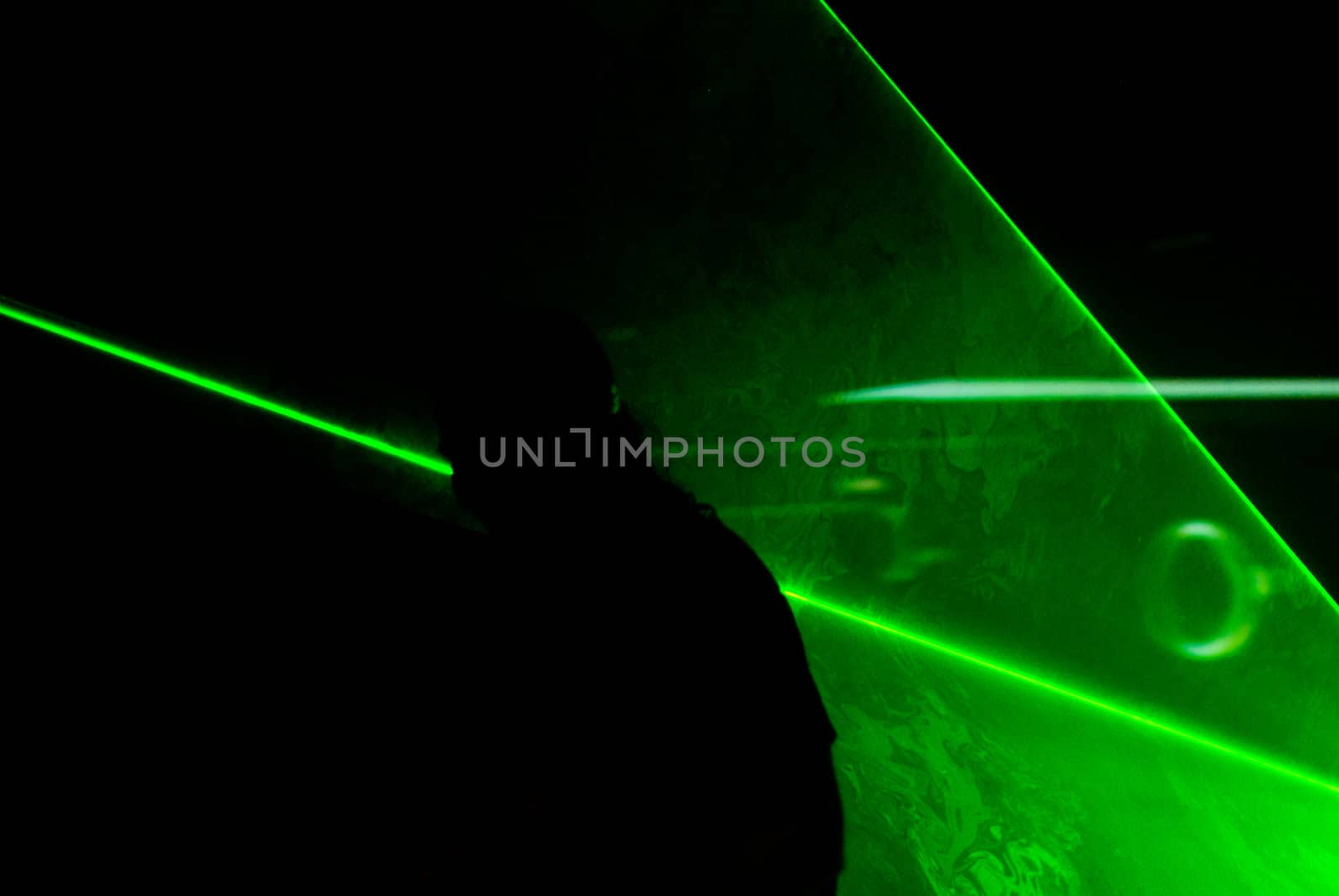 Silhouette of a man playing guitar surrounded by green lasers.