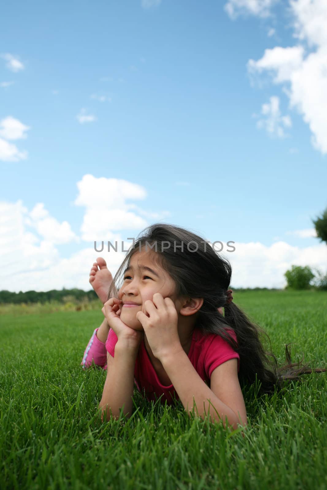 Little girl lying on grass in summer