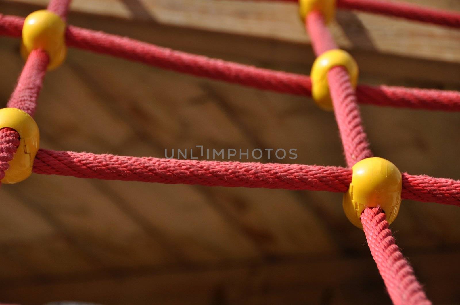 Climbing ropes construction on playground - red ropes with yellow elements and blurred backround