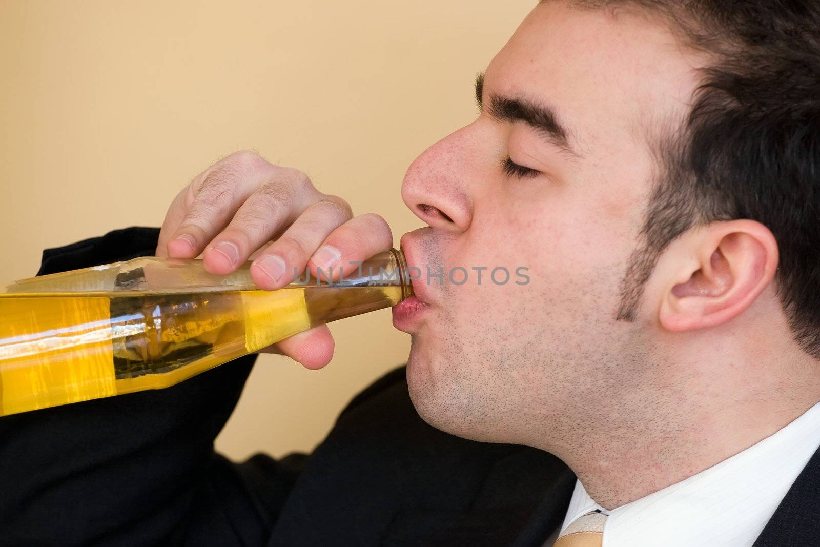 A young business man enjoying a nice cold bottle of beer after work.