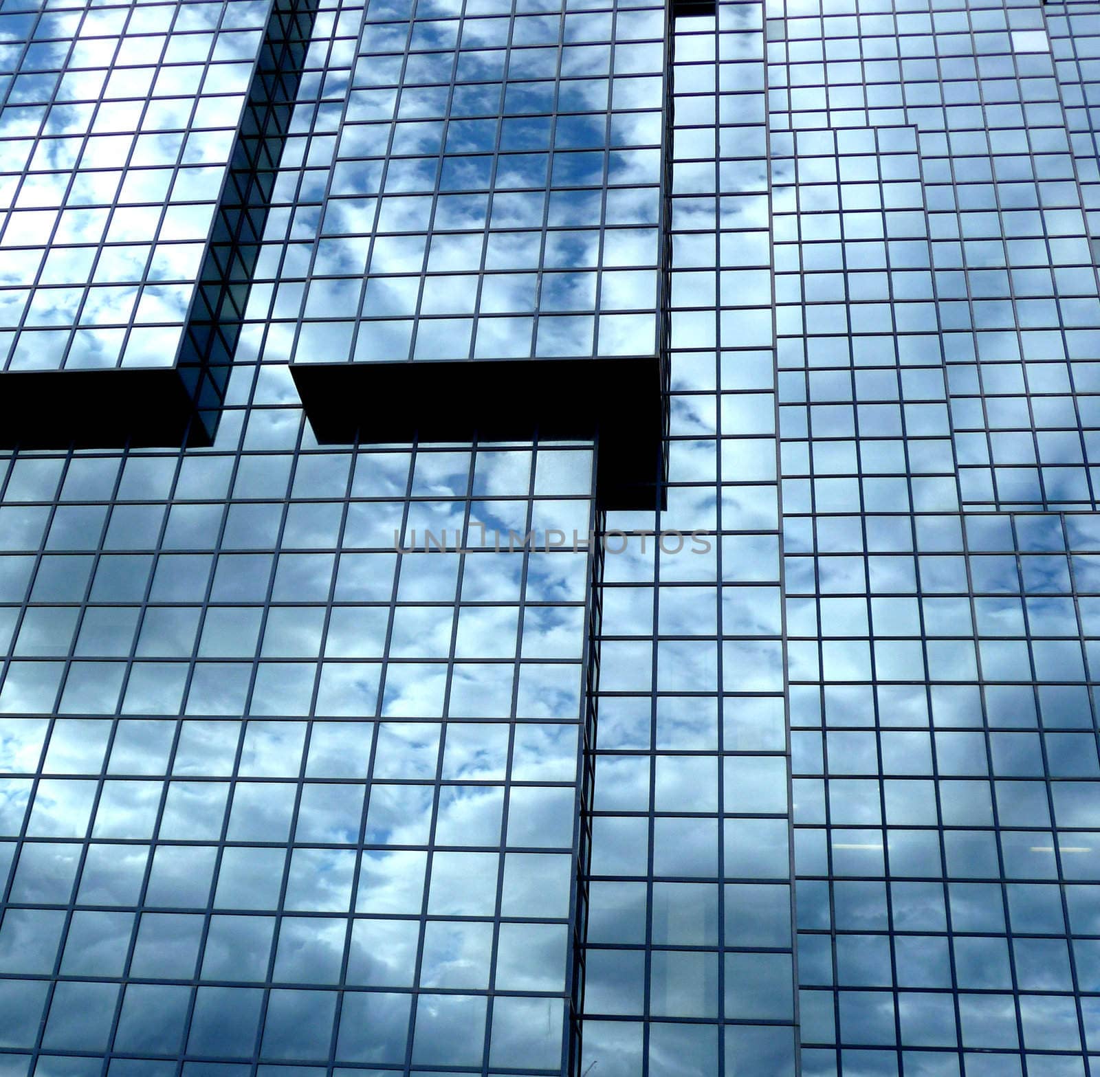 A building that has an interesting set of windows, with clouds reflected in the glass.