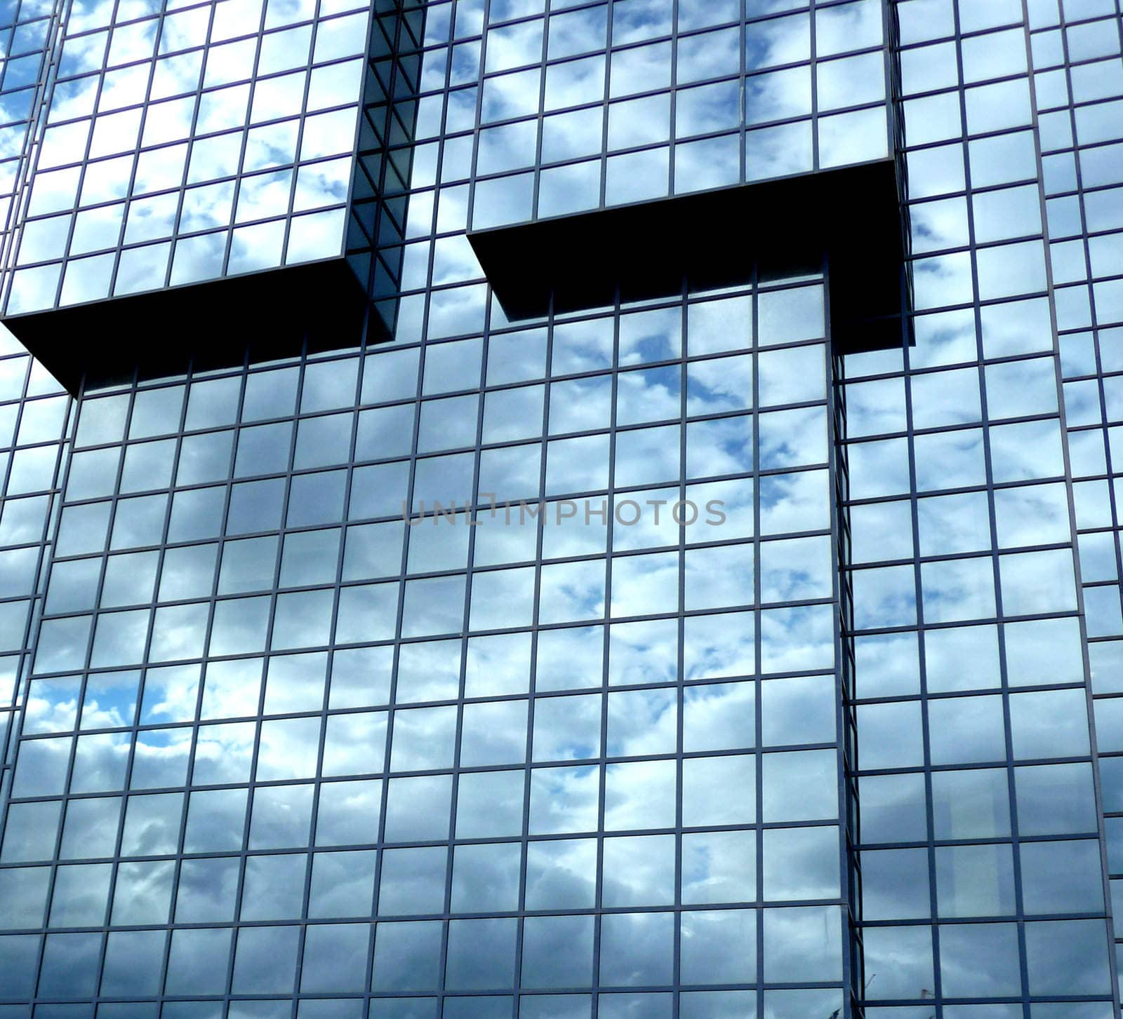 A building that has an interesting set of windows, with clouds reflected in the glass.
