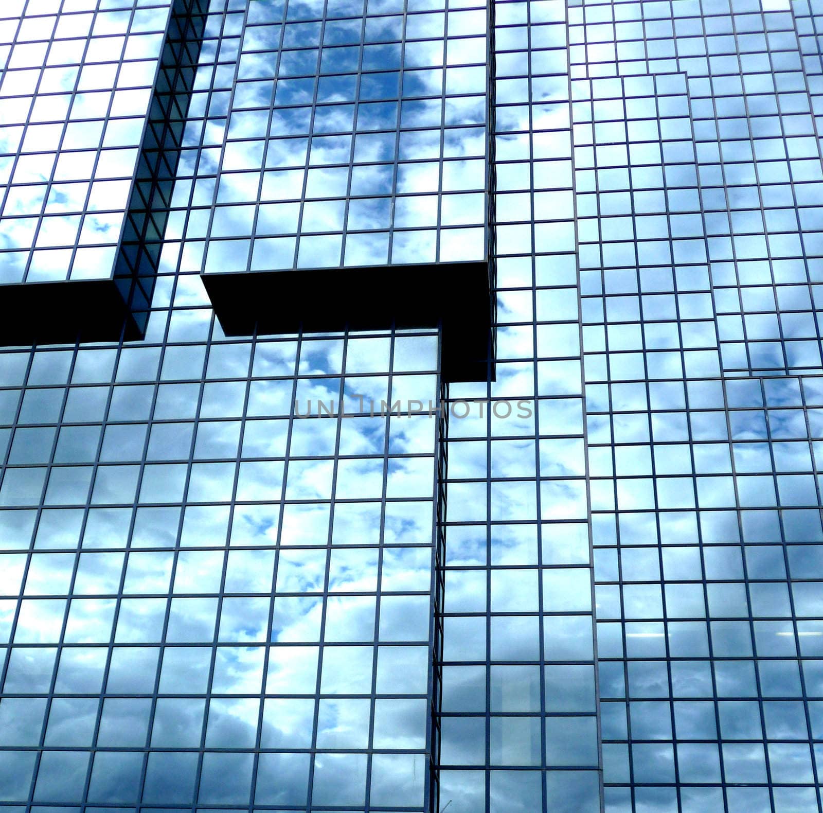 A building that has an interesting set of windows, with clouds reflected in the glass.
