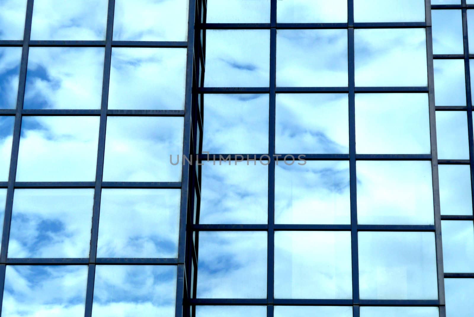 A building that has an interesting set of windows, with clouds reflected in the glass.
