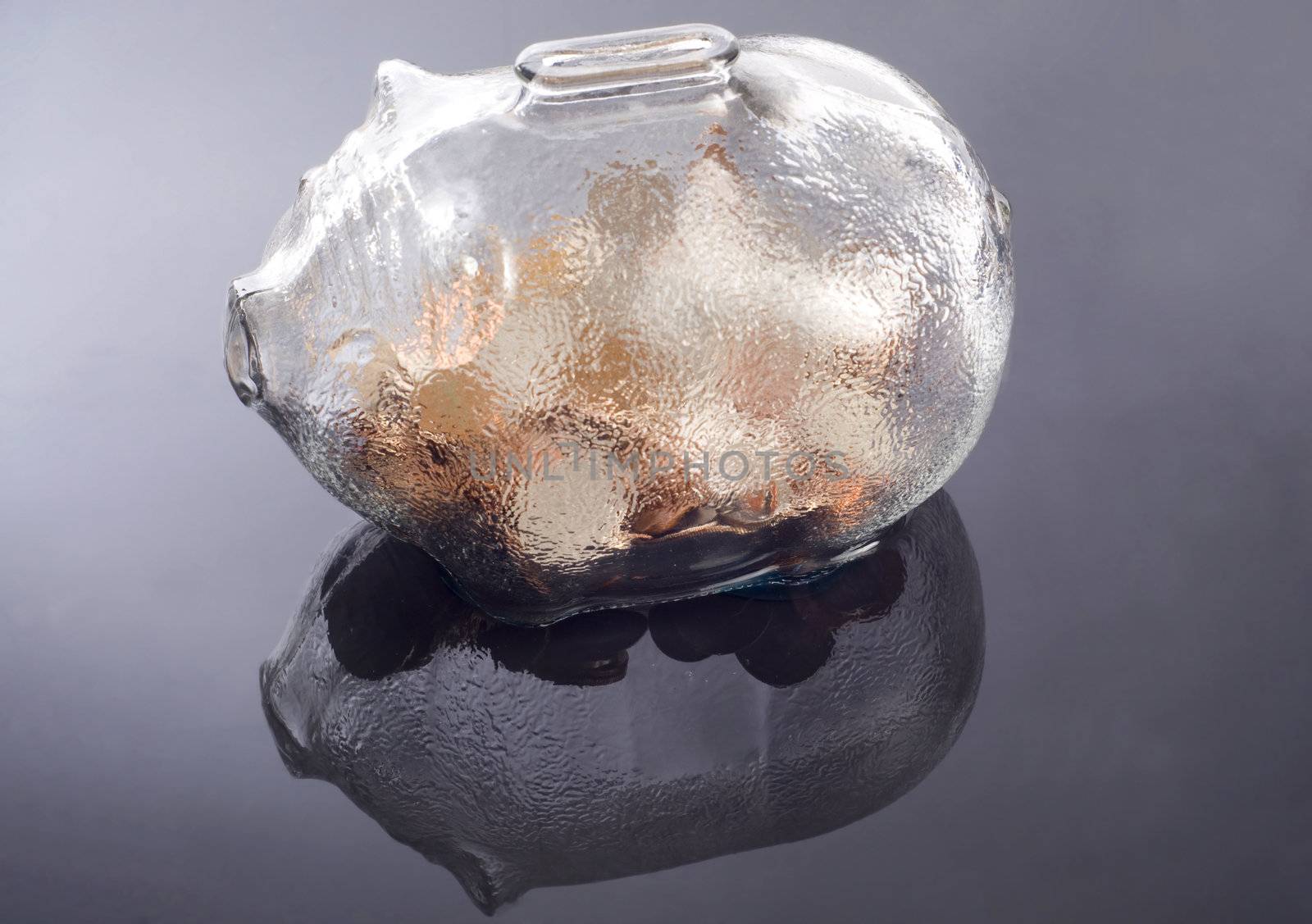 a glass piggy bank with coins  feflecting on a water base background