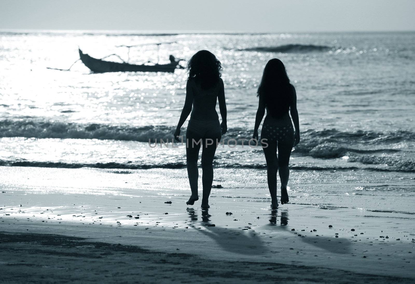 Two silhouettes of girls at coast of ocean