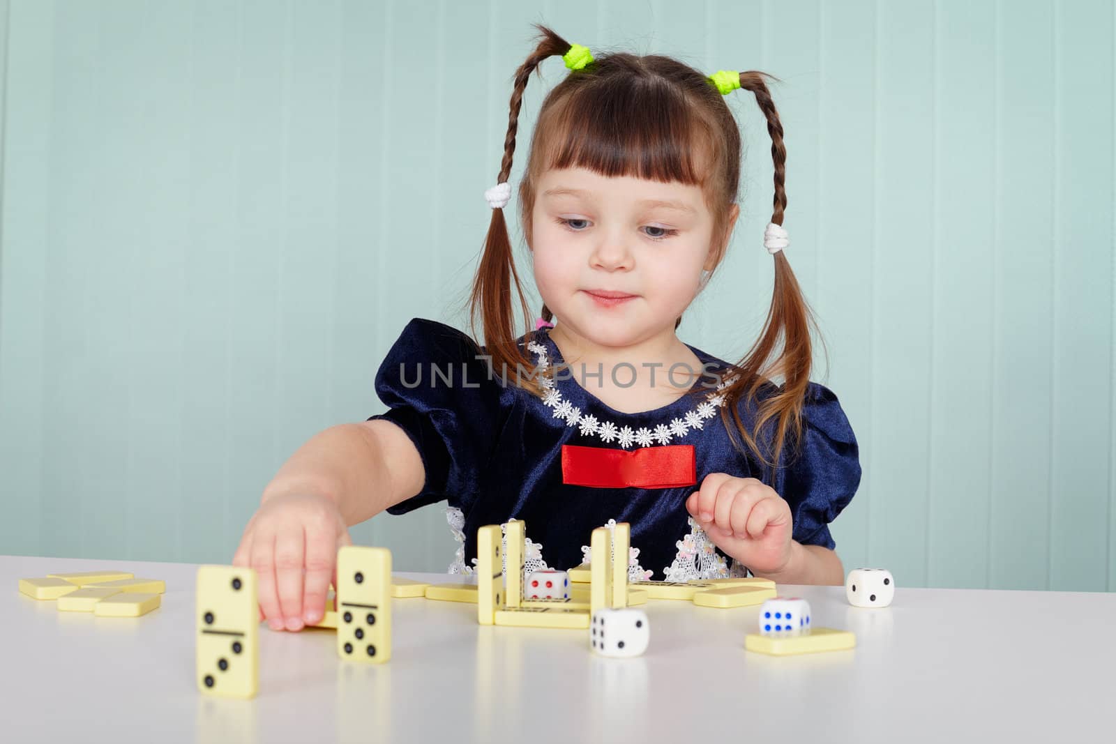 The little girl playing with dominoes sitting at the table