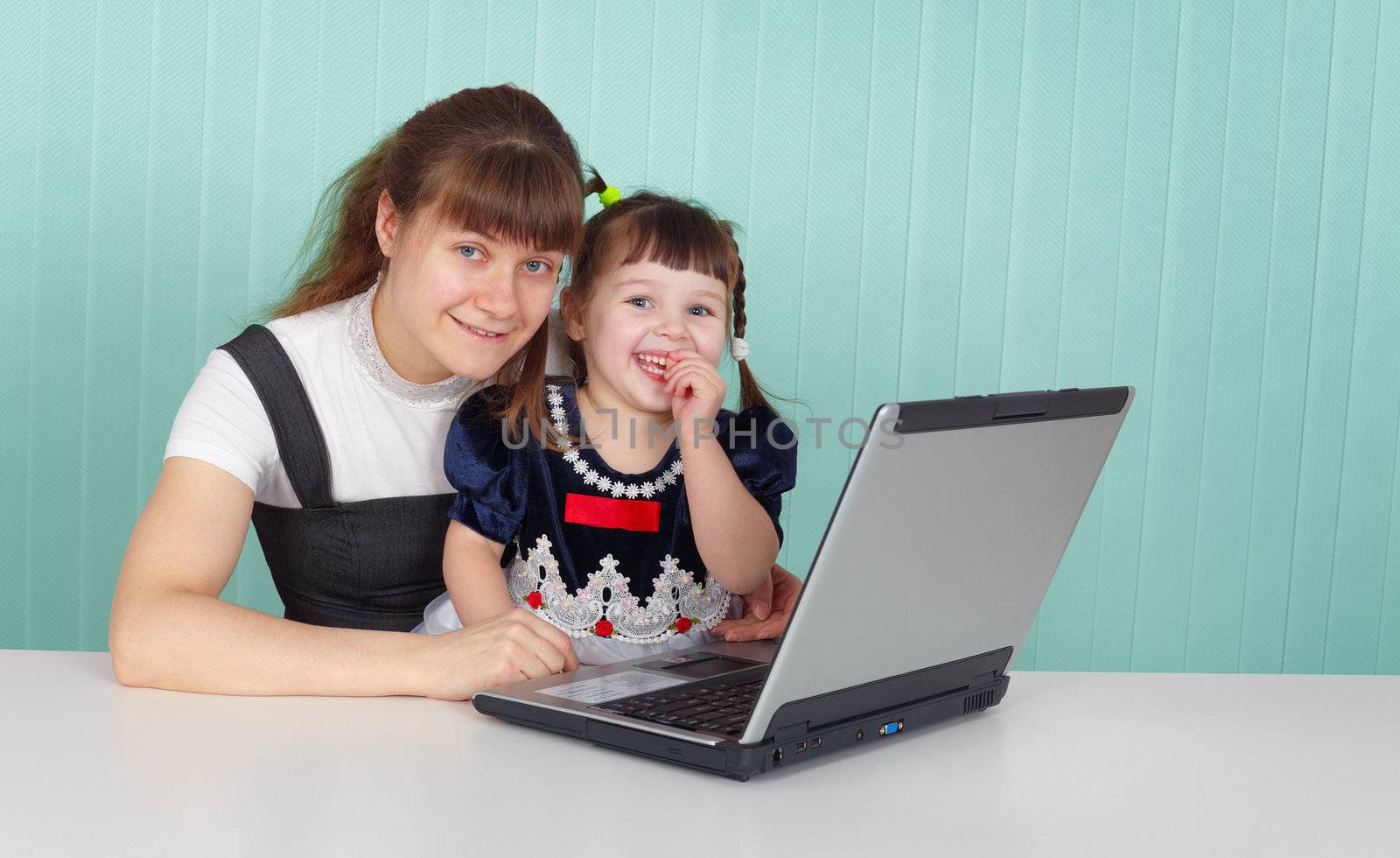 Mom and daughter happily playing with laptop