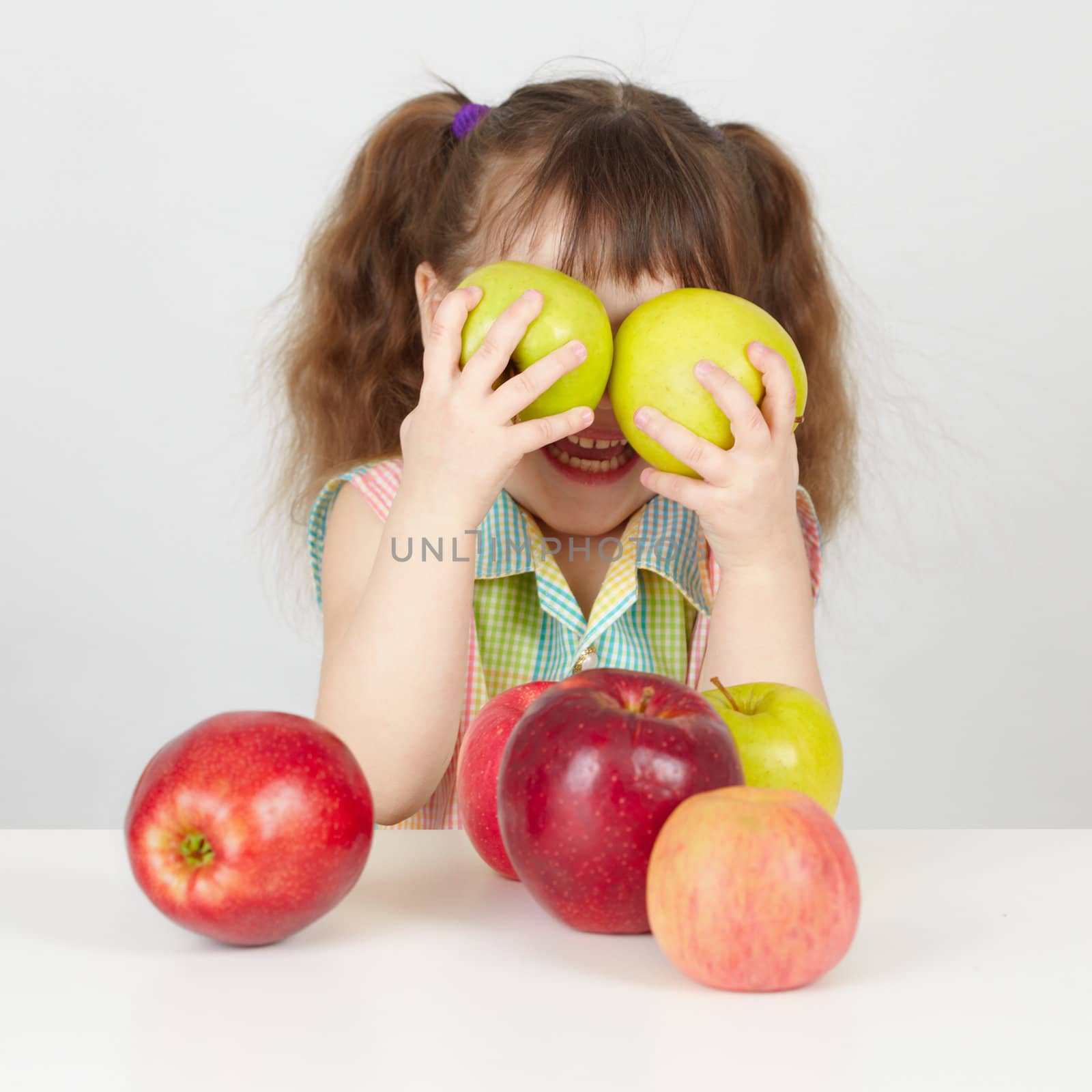 Funny child playing with two apples on table