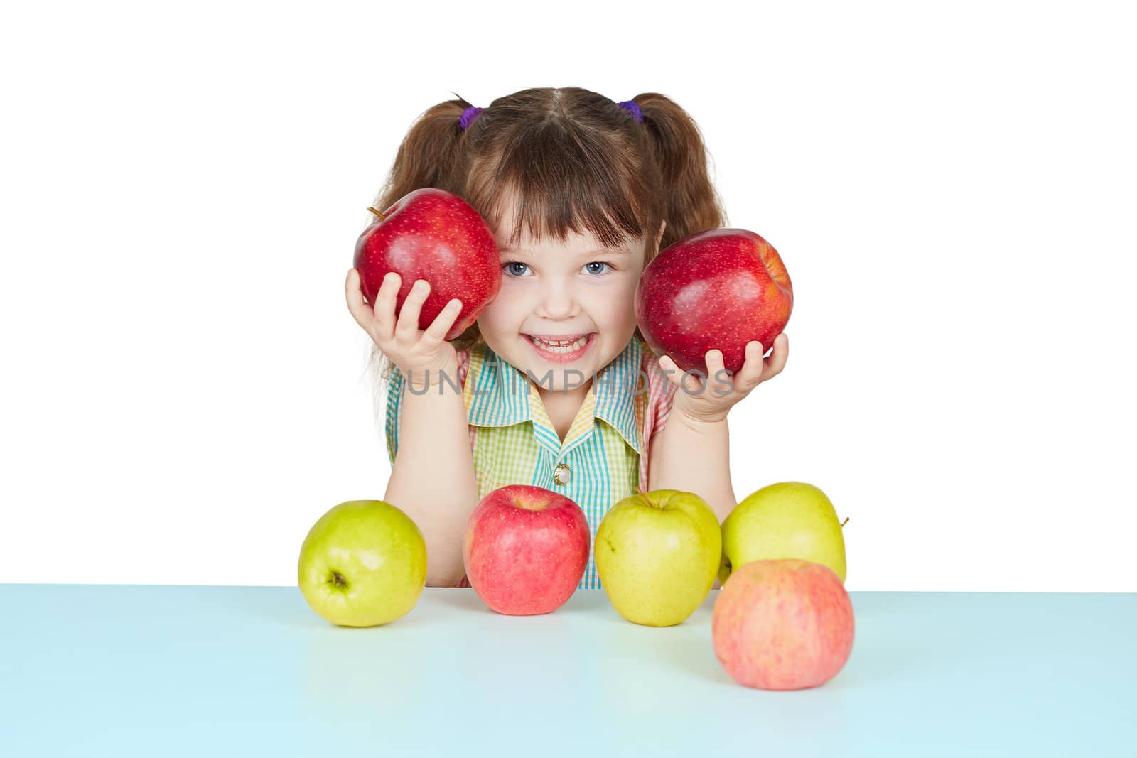 Funny child playing with two red apples on blue table