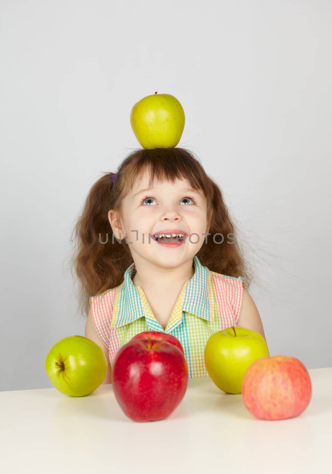 Green apple on the head of a cheerful girl