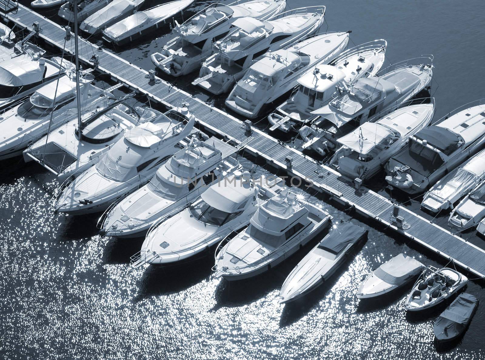 Blue toned image of luxury boats moored on Monaco jetty