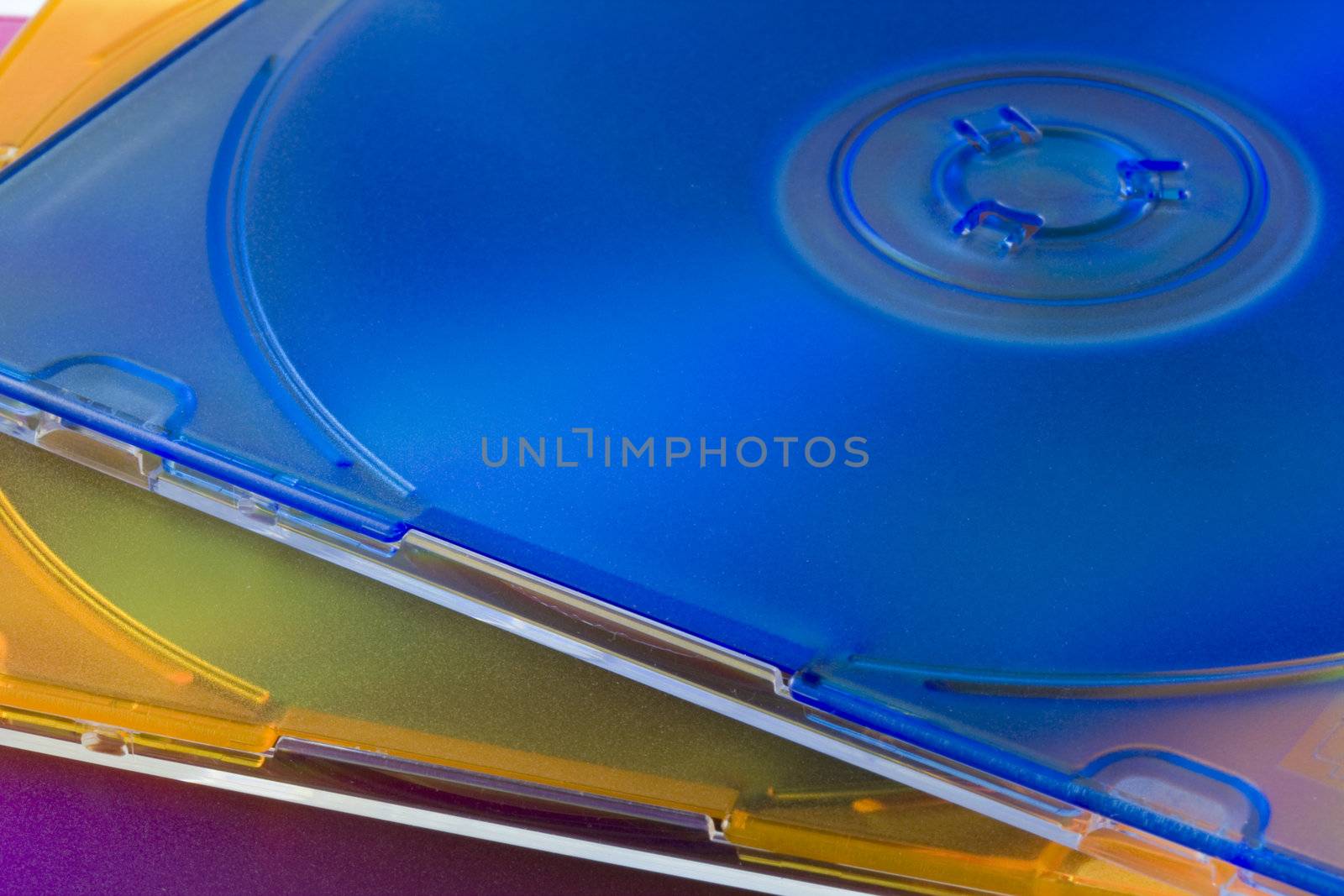 three CD or DVD optical disks in blue, orange and magenta jewel cases