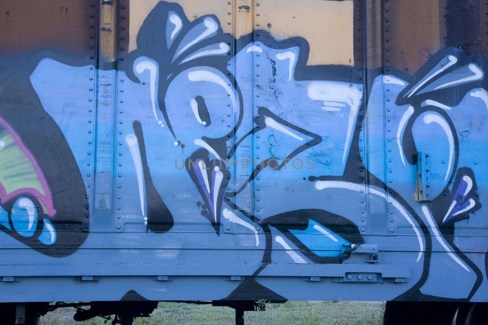 blue graffiti on a rusty freight train cart