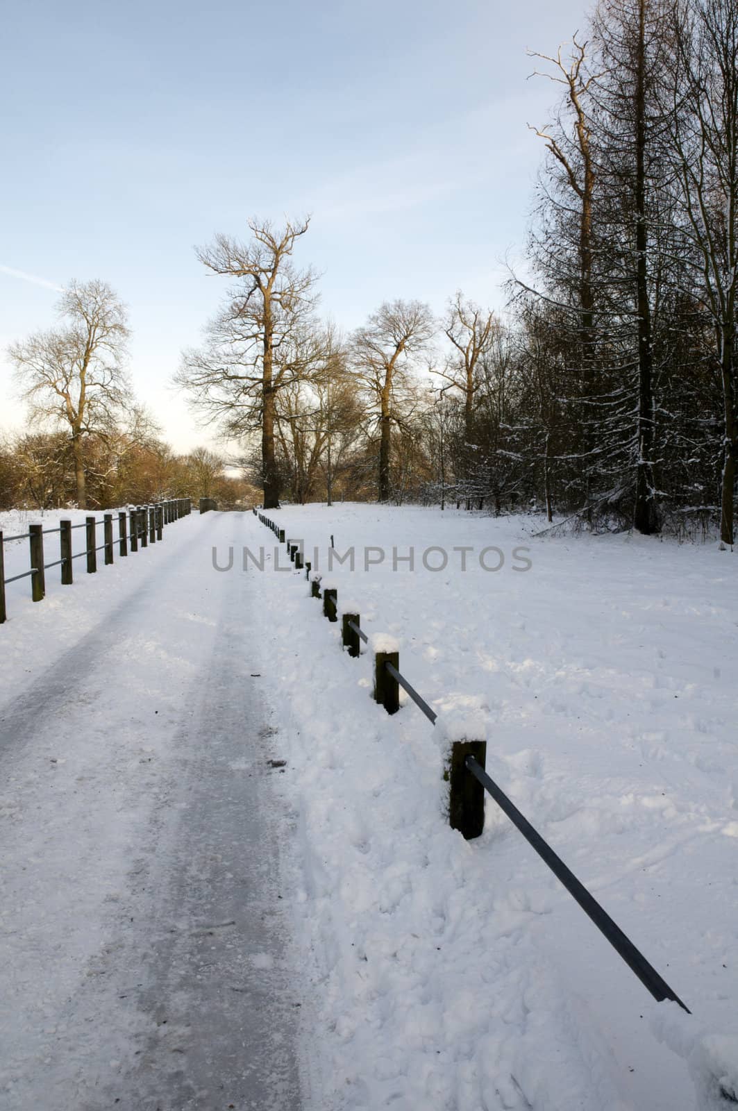 A footpath covered in snow with a fence