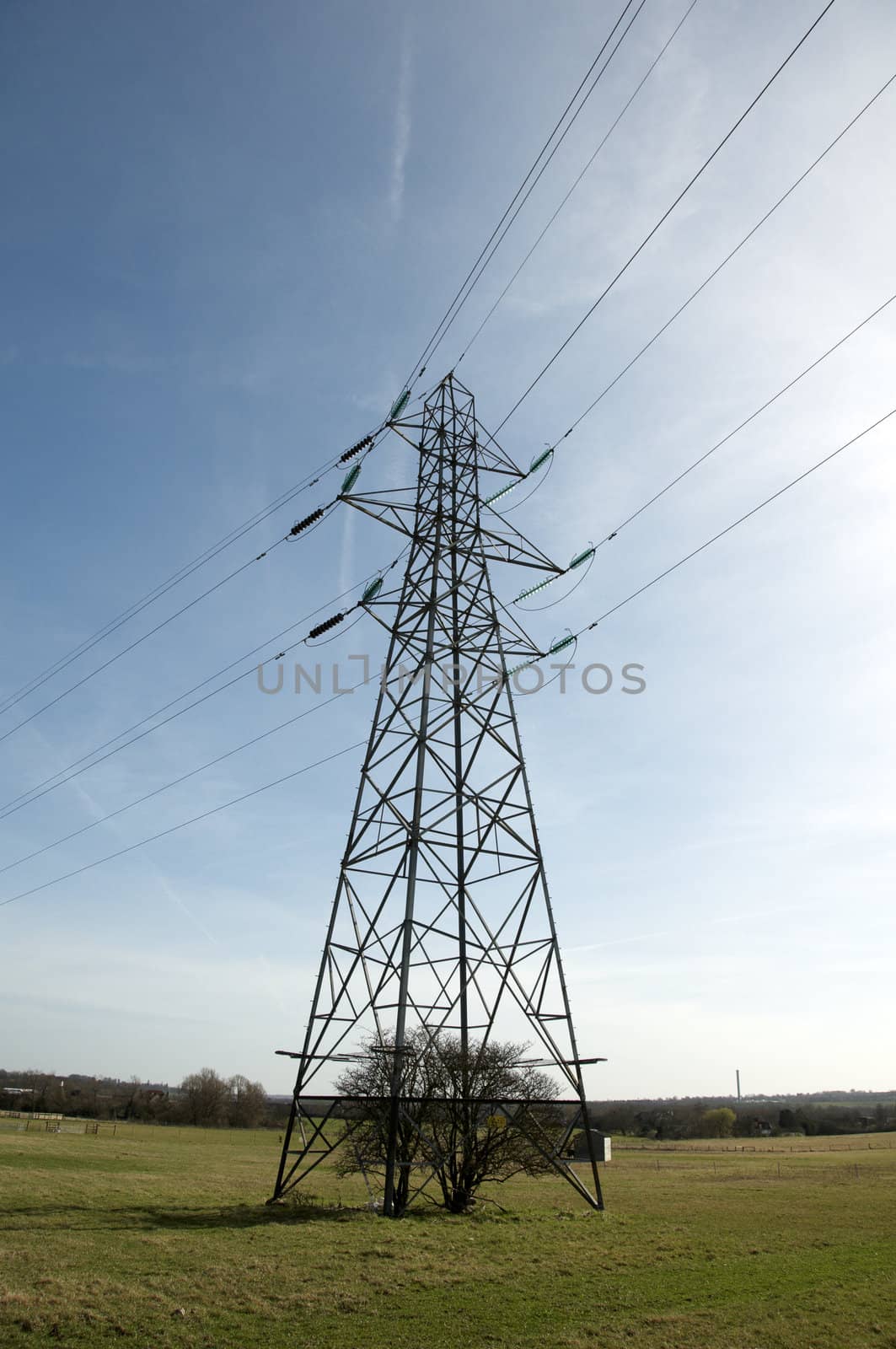 An electrical pylon in a field with a blue sky